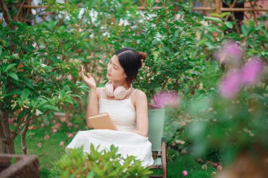 Kız bahçede kitap okuyor.