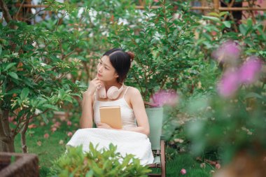 Kız bahçede kitap okuyor.