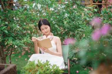 Kız bahçede kitap okuyor.