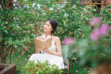 Kız bahçede kitap okuyor.