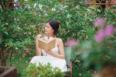 Kız bahçede kitap okuyor.