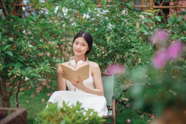 Kız bahçede kitap okuyor.