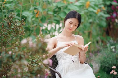 Kız bahçede kitap okuyor.