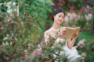 Kız bahçede kitap okuyor.