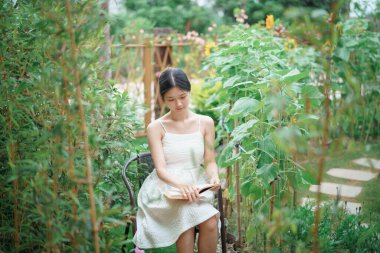 Kız bahçede kitap okuyor.