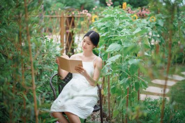 Kız bahçede kitap okuyor.