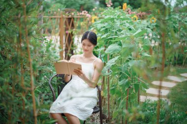 Kız bahçede kitap okuyor.