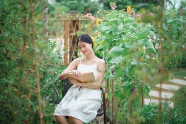 Kız bahçede kitap okuyor.