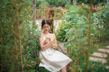 Kız bahçede kitap okuyor.