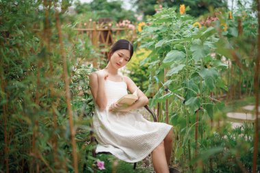 Kız bahçede kitap okuyor.