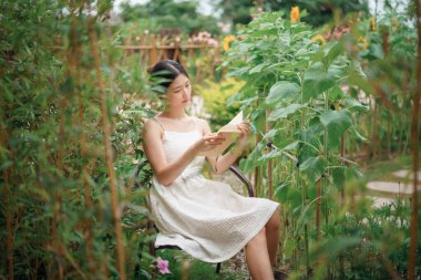 Kız bahçede kitap okuyor.