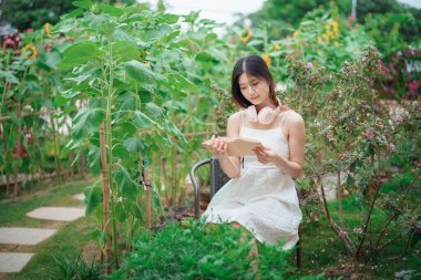 Kız bahçede kitap okuyor.