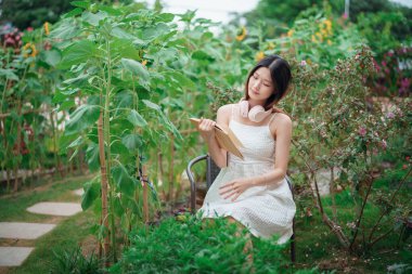 Kız bahçede kitap okuyor.