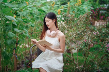 Kız bahçede kitap okuyor.