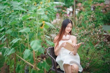 Kız bahçede kitap okuyor.