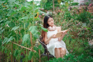 Kız bahçede kitap okuyor.