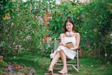 Kız bahçede kitap okuyor.