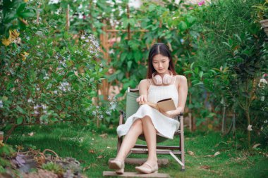 Kız bahçede kitap okuyor.