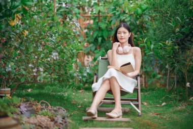 Kız bahçede kitap okuyor.