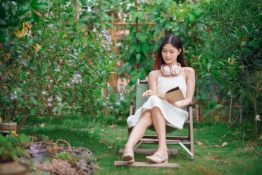 Kız bahçede kitap okuyor.