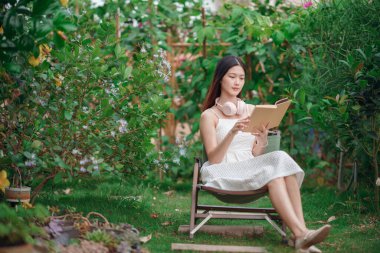 Kız bahçede kitap okuyor.