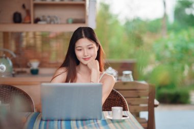 Genç kızlar bahçede dizüstü bilgisayar kullanır.