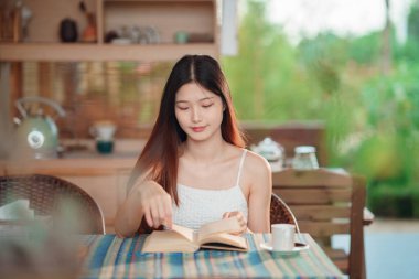 Kız bahçede kitap okuyor.