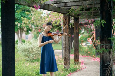 Kız bahçede keman çalıyor.