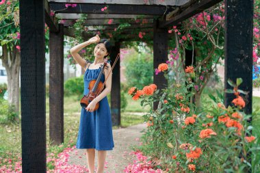 Kız bahçede keman çalıyor.