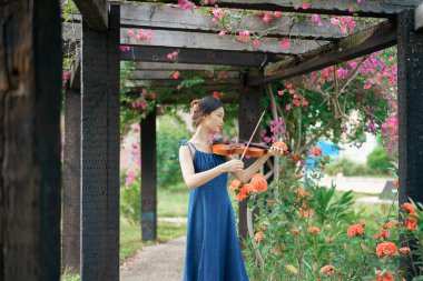 Kız bahçede keman çalıyor.
