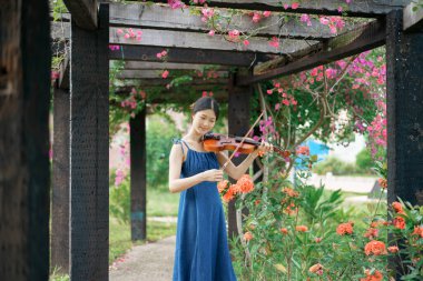 Kız bahçede keman çalıyor.