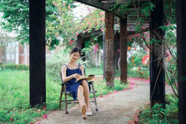 Kız bahçede kitap okuyor.