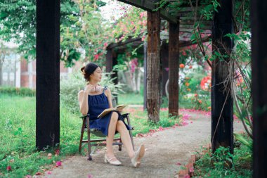 Kız bahçede kitap okuyor.