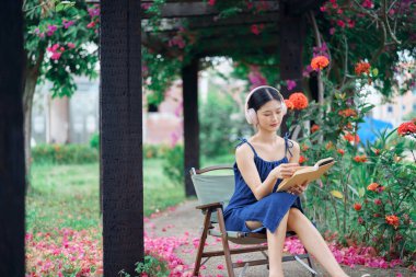 Kız bahçede kitap okuyor.