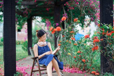 Kız bahçede kitap okuyor.