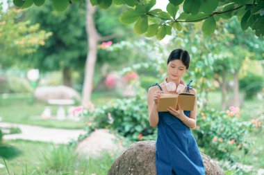 Kız bahçede kitap okuyor.