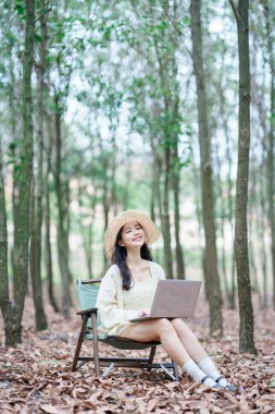 Kız ormanda dizüstü bilgisayar kullanıyor.