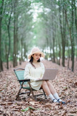 Kız ormanda dizüstü bilgisayar kullanıyor.