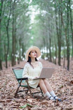 Kız ormanda dizüstü bilgisayar kullanıyor.