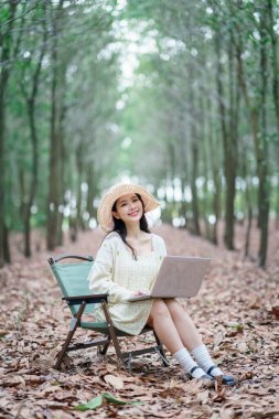 Kız ormanda dizüstü bilgisayar kullanıyor.