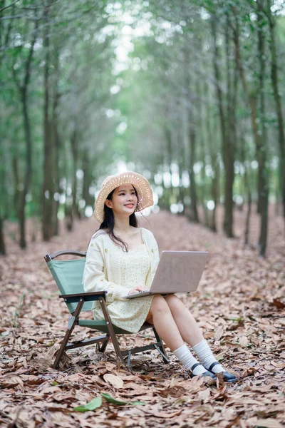 Kız ormanda dizüstü bilgisayar kullanıyor.