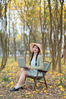 Kız ormanda dizüstü bilgisayar kullanıyor.