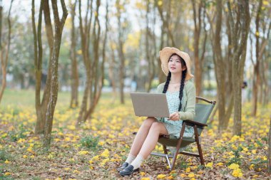 Kız ormanda dizüstü bilgisayar kullanıyor.