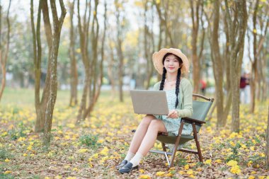 Kız ormanda dizüstü bilgisayar kullanıyor.