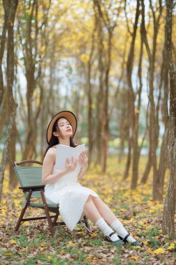 Kız ormanda kitap okuyor.