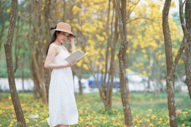 Kız ormanda kitap okuyor.