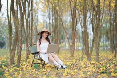 Kız ormanda dizüstü bilgisayar kullanıyor.