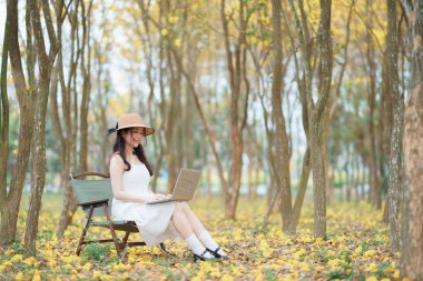 Kız ormanda dizüstü bilgisayar kullanıyor.