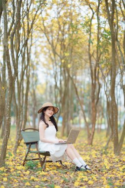 Kız ormanda dizüstü bilgisayar kullanıyor.