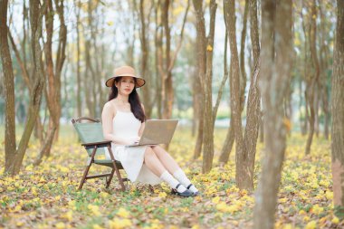 Kız ormanda dizüstü bilgisayar kullanıyor.